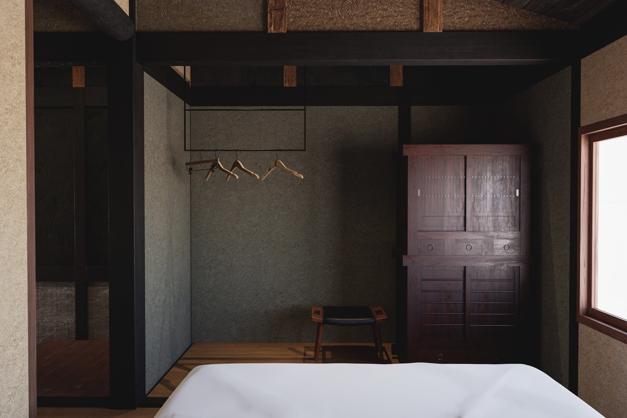 A quiet bedroom of dark timber and crafted cabinetry.